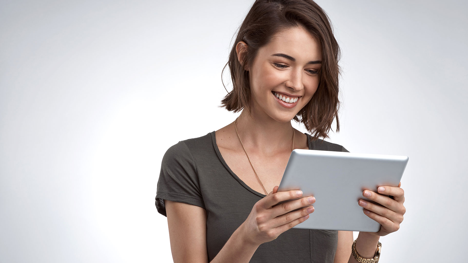 Photo of a woman smiling, using a tablet